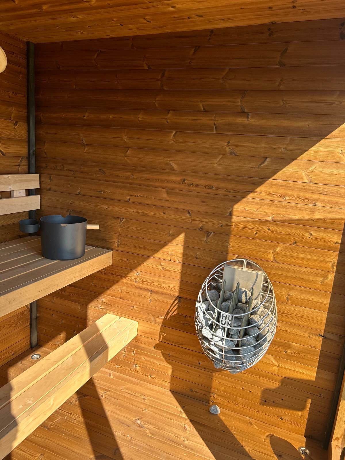 Monarch King Traditional Outdoor Sauna interior view with heater and bucket laddle termometer