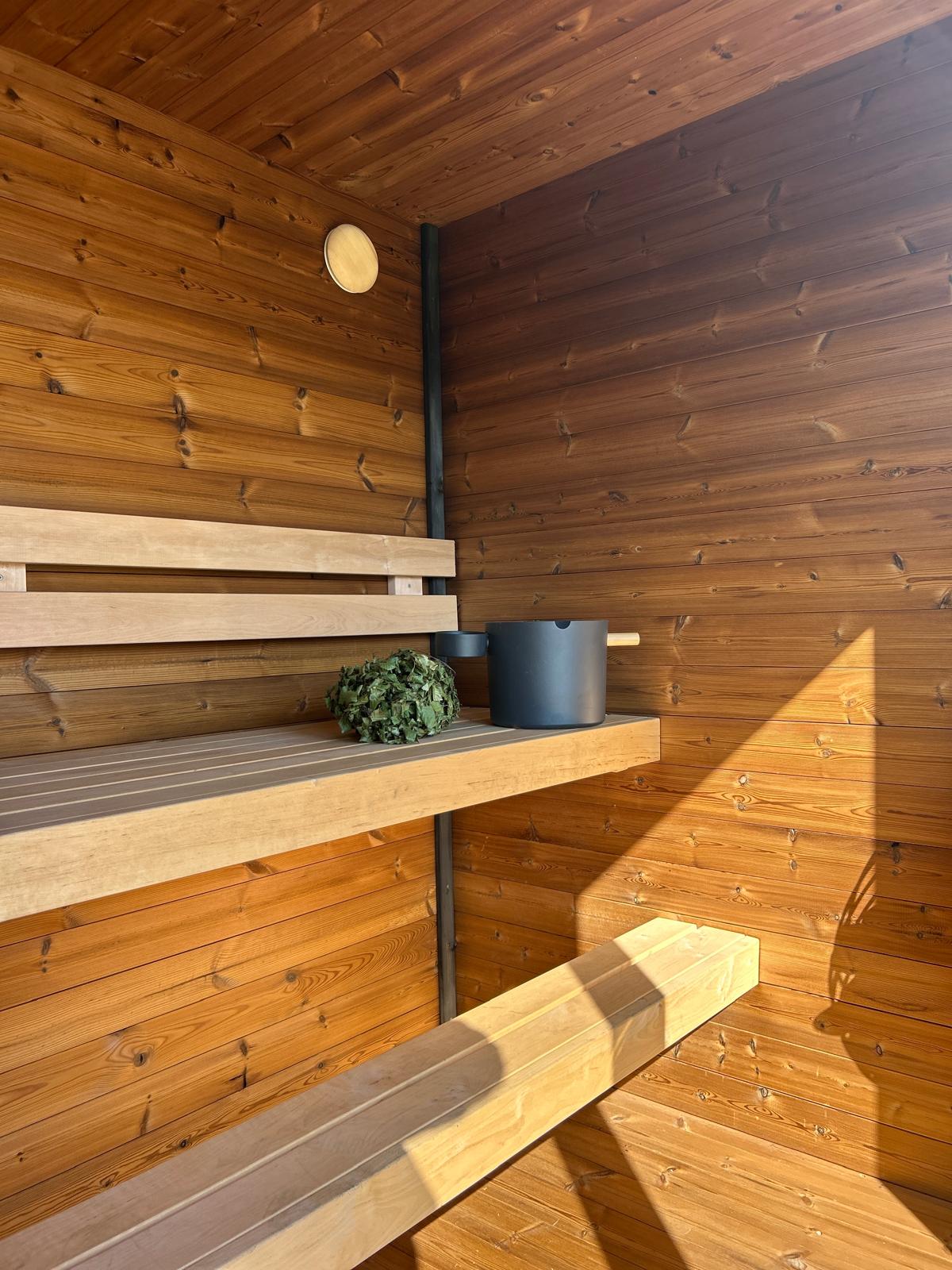 Grand Monarch Traditional Outdoor Sauna Interior view with a bucket laddle termometer