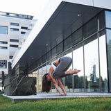 Woman doing a yoga pose beside a Loki Calacatta Black cold plunge outside a glass building