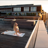 Woman relaxing on a rooftop deck beside a Loki Porfido Marrone cold plunge